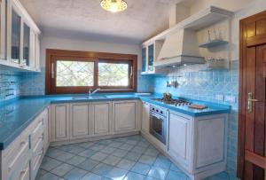 a blue kitchen with white cabinets and a sink at Hotel Nibaru in Porto Cervo