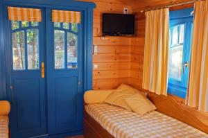 Habitación con puertas azules y TV en una cabina. en Roulotte De Charme, en Grasse