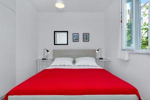 une chambre blanche avec une couverture rouge sur un lit dans l'établissement Apartments Franzeta, à Makarska