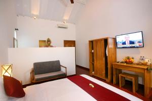 a bedroom with a bed and a chair and a television at Cokelat Guest House in Tanah Lot