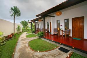 a house with a porch with a table and chairs at Cokelat Guest House in Tanah Lot