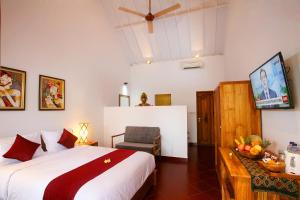 a bedroom with a bed and a chair and a tv at Cokelat Guest House in Tanah Lot +32 photos