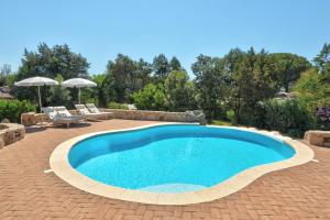a pool in a yard with chairs and an umbrella at Hotel Nibaru in Porto Cervo