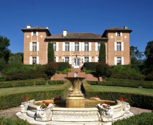 Residence Chateau de Barbet في Lombez: منزل كبير وامامه نافورة
