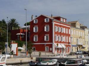 a large red building with boats docked in a harbor at Mare Mare Suites in Mali Lošinj