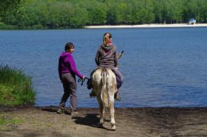 a woman leading a girl on a horse by a lake at La Cab'Ane in Saint-Jean-aux-Bois