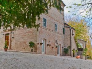 um grande edifício de tijolos com uma árvore em frente em Villa Funari Country House em Servigliano