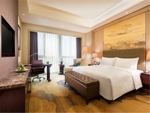 um quarto de hotel com uma cama grande e uma secretária em Wanda Realm Fushun em Fushun