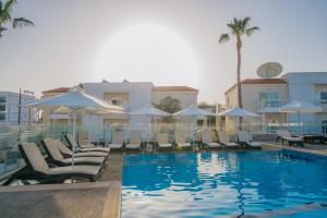 a pool with chairs and umbrellas next to a building at New Famagusta Hotel & Suites in Ayia Napa