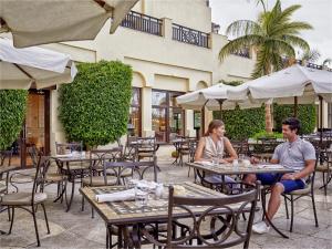 Steigenberger Aldau Beach Hotel في الغردقة: جلوس رجل وامرأة على الطاولات في مطعم خارجي