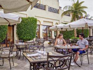 Ein Mann und eine Frau sitzen an Tischen in einem Restaurant im Freien in der Unterkunft Steigenberger Aldau Beach Hotel in Hurghada