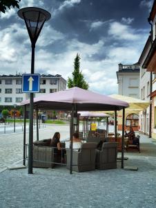twee mensen zitten onder een paraplu op straat bij Hotel Slovan in Jeseník
