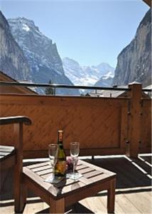 een fles wijn en twee glazen op een tafel bij Charming Penthouse in Lauterbrunnen