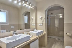 a white bathroom with two sinks and a shower at Hotel Nibaru in Porto Cervo