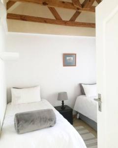 a white bedroom with two beds and a lamp at Milnerton Guesthouse in Cape Town