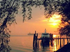 a boat is docked at a dock with the sunset at Lumut Valley Resort Condominium in Lumut