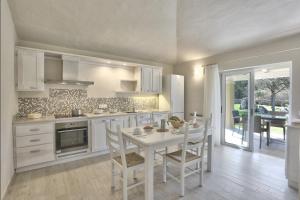 a white kitchen with a table and chairs in it at Hotel Nibaru in Porto Cervo