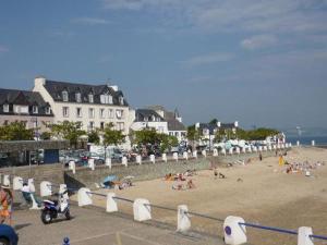 a beach with a group of people sitting on the sand at La Maison Bellevue in Saint-Efflam