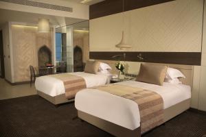 a hotel room with two beds and a mirror at Erbil Arjaan by Rotana in Erbil