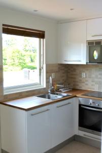 kuchnia z białymi szafkami, umywalką i oknem w obiekcie Room by Water w mieście Södertälje