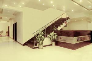 a lobby with a staircase and two potted plants at Hotel Metropolitan in Jaipur