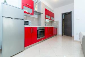 a red kitchen with white appliances and red cabinets at APARTMENT JURAŠIN in Kaštela +27 photos