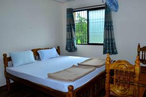 a bedroom with a bed with blue curtains and a window at Hills View Stay in Māvingundi