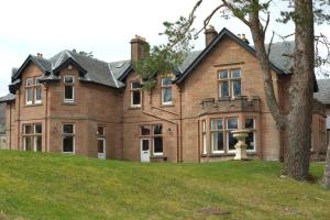a large house on a hill with a tree at Ledgowan Lodge Hotel in Achnasheen