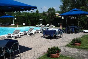 un gruppo di tavoli e sedie accanto alla piscina di Hotel Spresiano a Spresiano