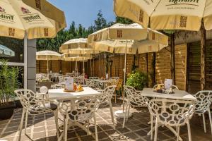 eine Terrasse mit weißen Tischen, Stühlen und Sonnenschirmen in der Unterkunft Hotel Novalis Dresden in Dresden