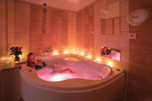 una donna sdraiata in una vasca da bagno con luci di Hotel Slovan a Jeseník