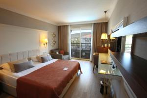 a hotel room with a large bed and a balcony at Fame Residence Kemer & Spa in Kemer