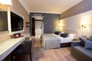 a hotel room with a bed and a tv and a couch at Fame Residence Kemer & Spa in Kemer