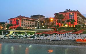 a group of chairs and umbrellas next to a hotel at Fame Residence Kemer & Spa in Kemer