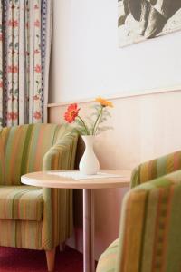 eine Vase mit Blumen auf einem Tisch neben zwei Stühlen in der Unterkunft Hotel Silbertal in Silbertal