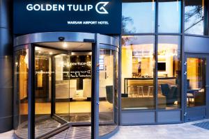 een toegang tot een winkel met een glazen draaideur bij Golden Tulip Warsaw Airport in Warschau