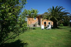 a house with two lawn chairs and a palm tree at Casa Gayol in El Franco
