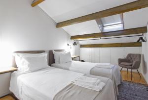 a bedroom with two beds and a chair in it at Casas do Rivoli in Porto