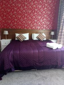 ジェドバラにあるThe Royal Hotelの赤い壁の紫色のベッドが備わるベッドルーム1室が備わります。