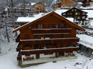 a large wooden building with snow on the roof at Roossi-Huus 2 in Wengen