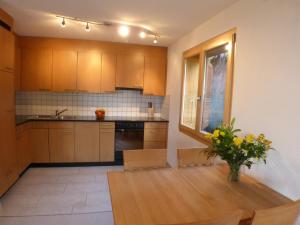 a kitchen with a table with a vase of flowers on it at Roossi-Huus 2 in Wengen