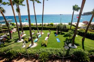 a group of people doing yoga in a park next to the ocean at Fame Residence Kemer & Spa in Kemer