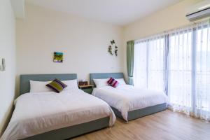 a bedroom with two beds and a large window at Wendy's home Toucheng Mansion B in Toucheng