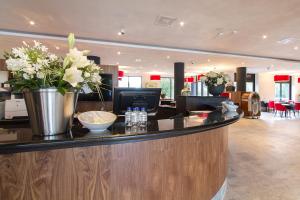 a lobby with a counter with flowers on it at Bastion Hotel Eindhoven Waalre in Eindhoven