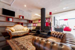 a living room with a leather couch and a television at Bastion Hotel Eindhoven Waalre in Eindhoven +18 photos
