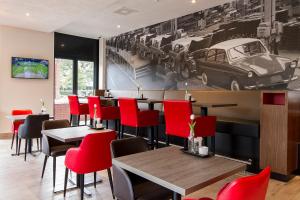 a restaurant with red chairs and tables and a picture of a car at Bastion Hotel Eindhoven Waalre in Eindhoven
