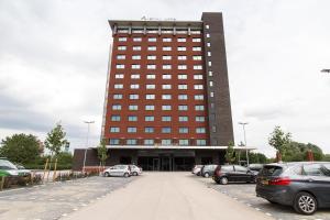 a large building with cars parked in a parking lot at Bastion Hotel Eindhoven Waalre in Eindhoven