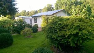 ein Haus mit einem Garten mit Büschen und Bäumen in der Unterkunft Ranczo Róż Wi-Ta in Przytór
