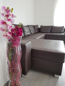 a vase filled with pink flowers next to a couch at Apartment by Janzen in Rheine