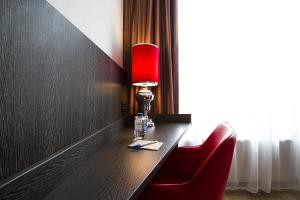 a red lamp on a table with a red chair at Bastion Hotel Eindhoven Waalre in Eindhoven